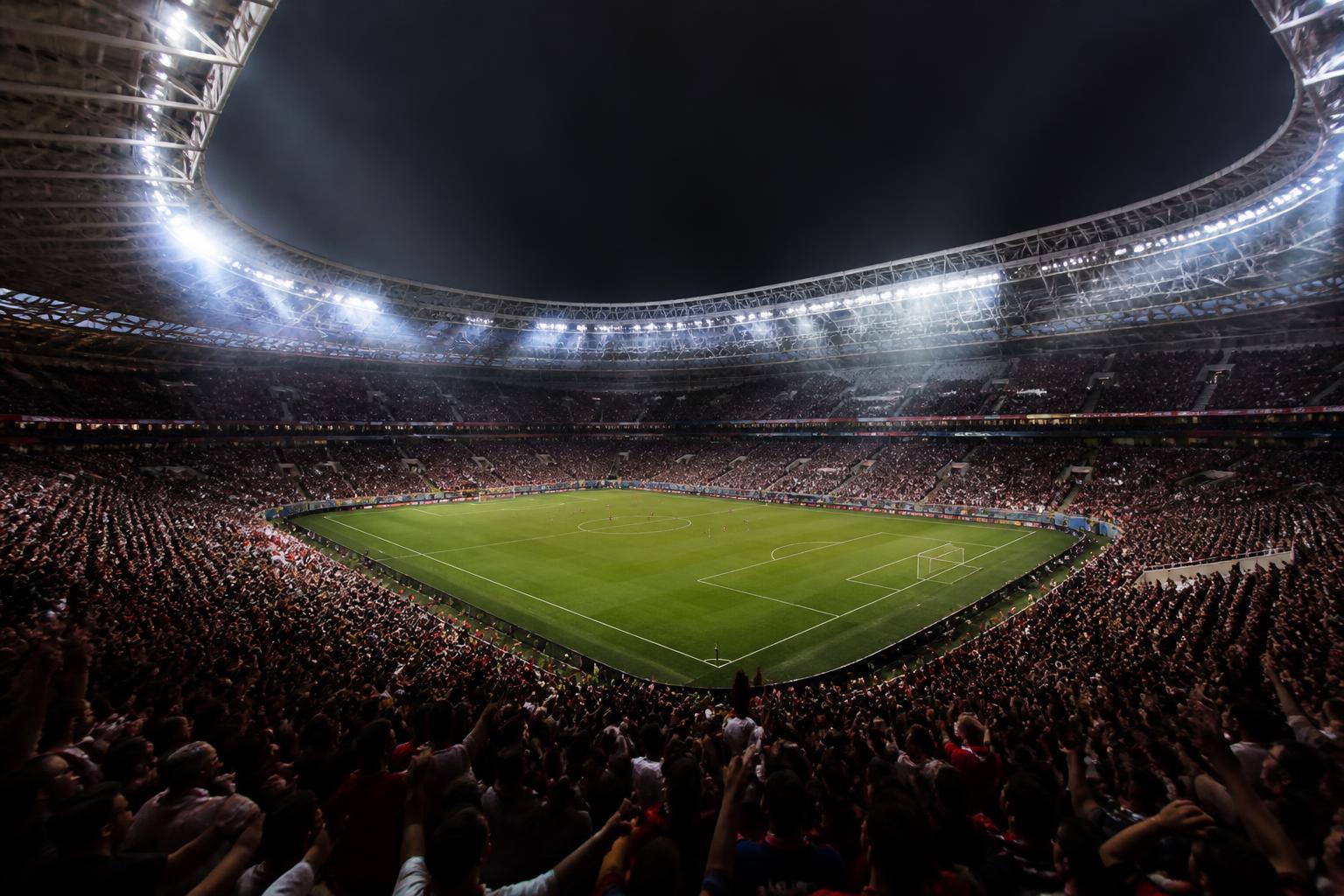 Packed modern stadium under floodlights at night